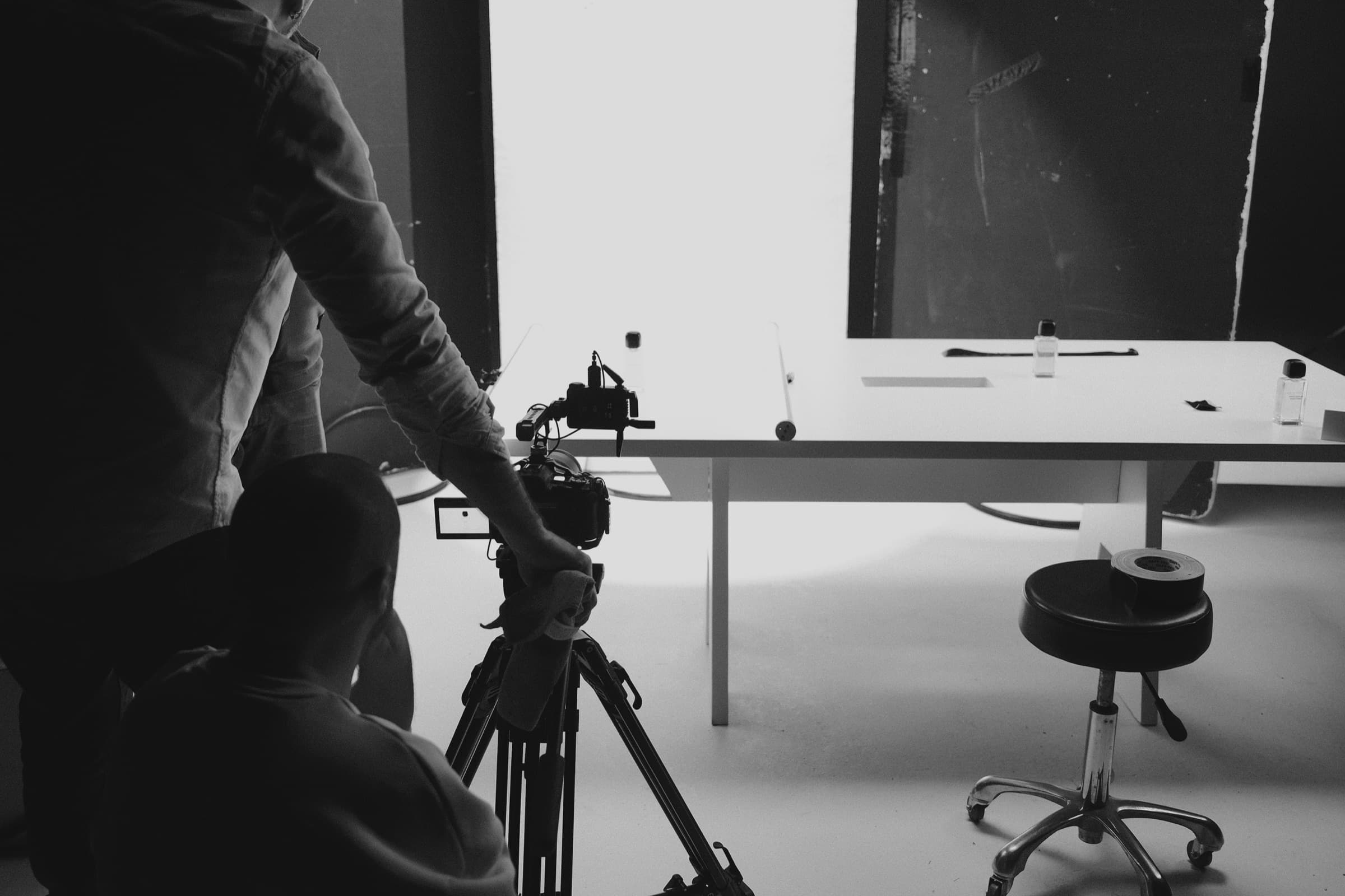 A camera operator filming the table from behind a tripod